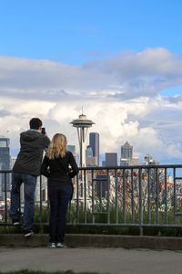 Rear view of friends standing against sky