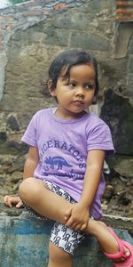 Portrait of cute girl sitting on rock