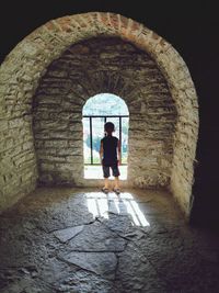 Rear view of boy standing at window of historic building