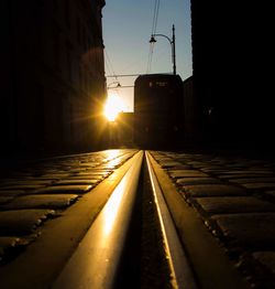 Surface level of railroad tracks against sky during sunset
