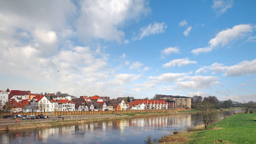 Buildings by river against sky