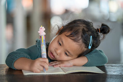 Portrait of girl holding pencils on table