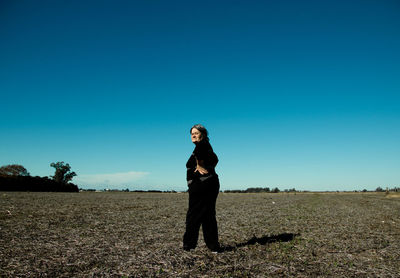 Portrait of woman standing on land against clear blue sky