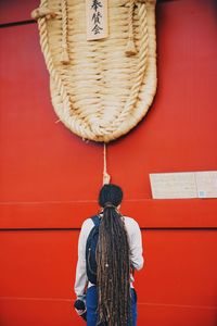 Rear view of woman standing against red wall