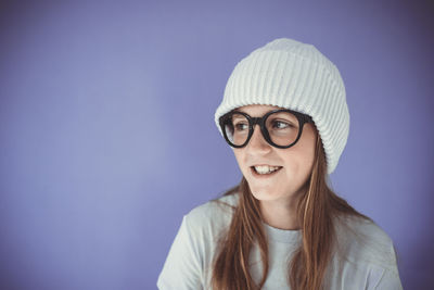 Portrait of young woman wearing sunglasses against blue background