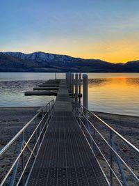 Pier over lake against sky during sunset