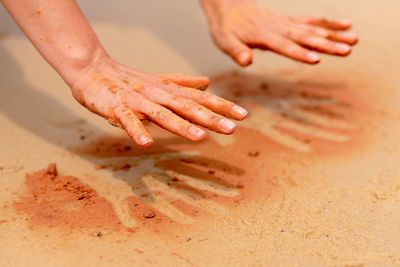 Cropped hands playing with sand at beach