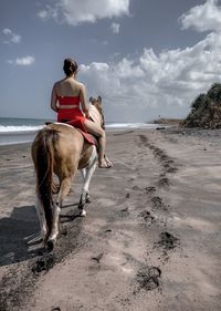 Woman riding horse on beach