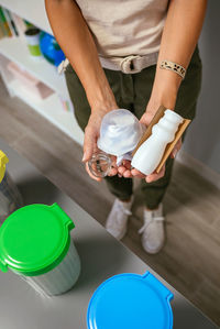 Female teacher holding waste to recycle with selective trash bins in foreground