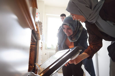 Family checking food for eid al-fitr in oven