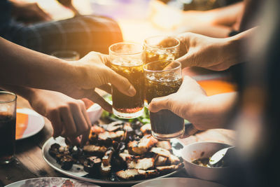 Close-up of hands toasting drink over table