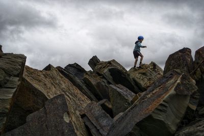 Low angle view of man standing on rock against sky