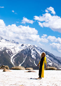 Rear view of woman standing on mountain against sky