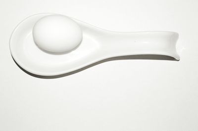 Close-up of egg in spoon over white background