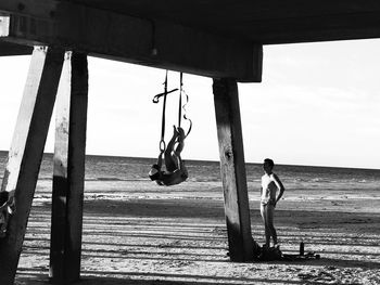 Side view of shirtless man on beach against sky