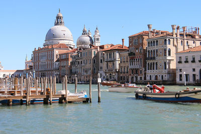 Boats in canal amidst buildings against clear sky, venice 