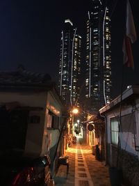 Illuminated street amidst buildings in city at night