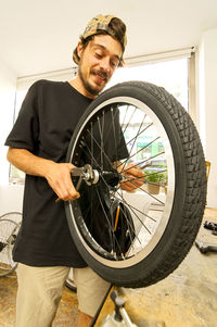 Young man repairing bicycle tire in workshop