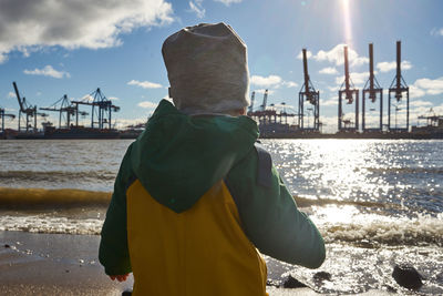 Rear view of man standing at beach against sky