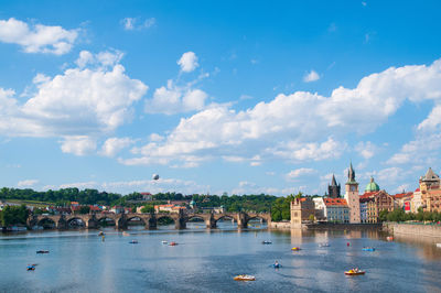 Bridge over river by buildings in city against sky