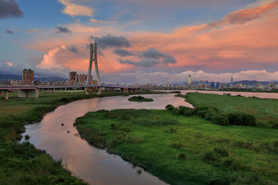 Bridge over river against cloudy sky