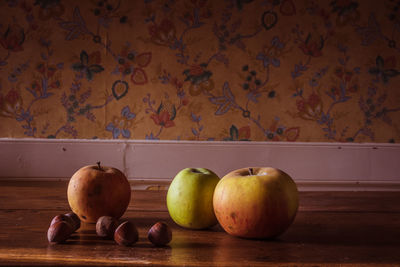 Close-up of apples on table against wall