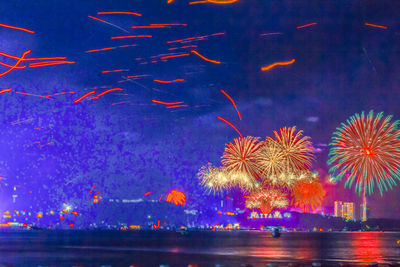 Low angle view of firework display over sea against sky at night