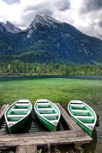 Boats moored on lake against mountains