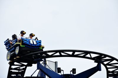 Low angle view of people at amusement park against sky