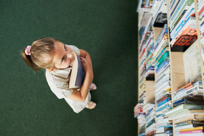 Student looking at top bookshelf in school library. smart girl selecting books. back to school