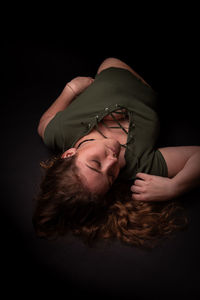 Portrait of woman lying down against black background