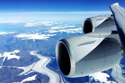 Airplane flying over snowcapped mountains against sky