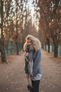 Young woman standing against trees