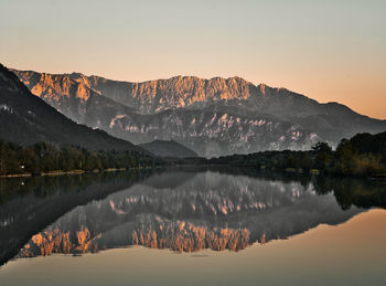 Scenic view of lake by mountains against sky during sunset