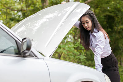 Businesswoman looking at car engine