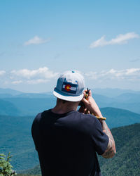 Rear view of man standing on mountain against sky