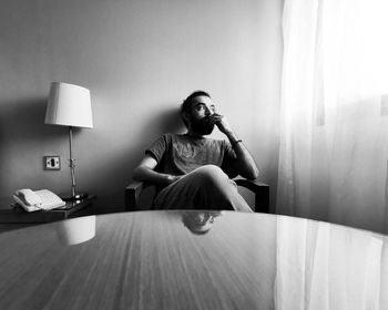 Full length of man sitting on sofa at home