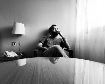 Man looking away sitting on chair at home