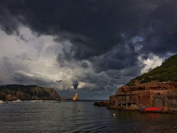 Town by sea against cloudy sky