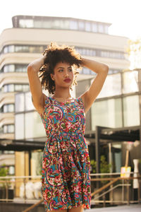 Fashionable young woman with curly hair looking away in city