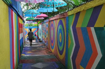 Rear view of man walking on multi colored wall