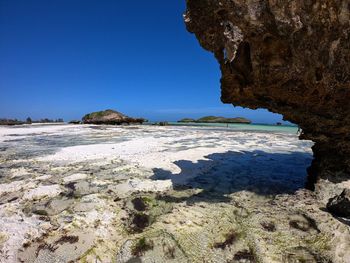 Rock formation on beach against clear blue sky