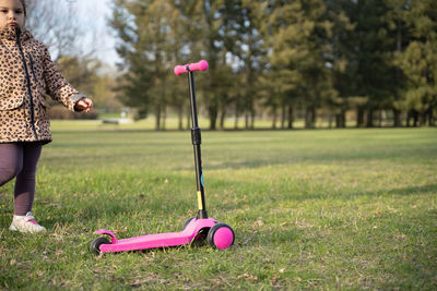 Girl standing by scooter in park