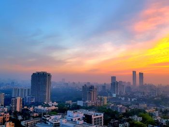 View of cityscape against cloudy sky during sunset