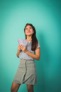 Portrait of young woman standing against blue background