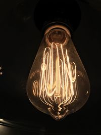 Low angle view of illuminated light bulb against black background