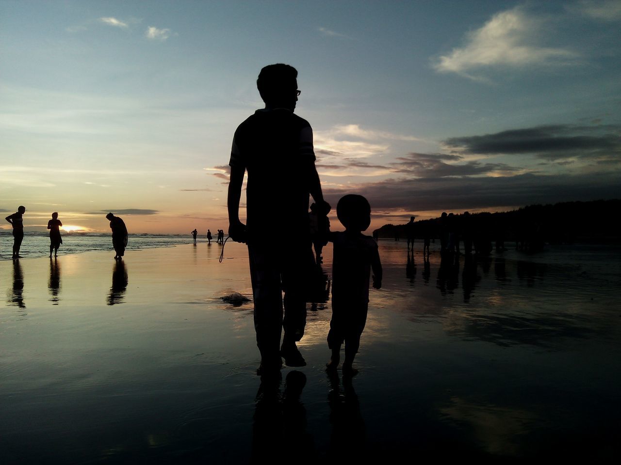 water, sea, sunset, silhouette, sky, lifestyles, standing, leisure activity, beach, reflection, men, tranquility, full length, shore, tranquil scene, rear view, scenics, beauty in nature