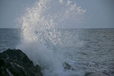 Waves splashing on sea against sky
