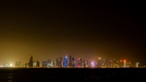Illuminated buildings in city against sky at night