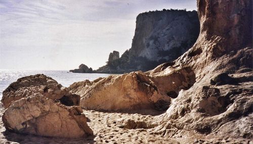 Rock formation on sea shore against sky